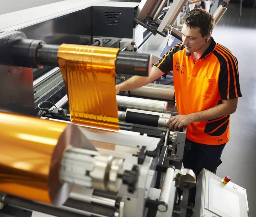 Hot foil stamping machine applying metallic foil to roll labels at Gervin Printing factory